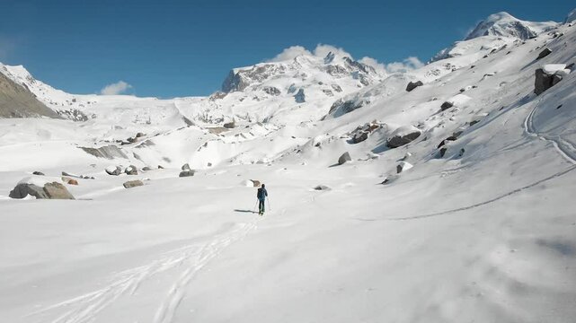 Aerial flyover over a skier and Gorner glacier in Zermatt, Switzerland covered in snow on a sunny winter ski tour next to the tallest peaks of the Swiss Alps with a view of Monte Rosa in background.