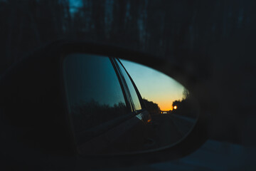 Fototapeta premium The dawn sky is reflected in the side mirror of the car