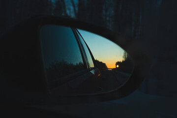 The dawn sky is reflected in the side mirror of the car