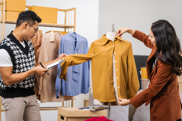 Businessman and woman, both fashion designers and entrepreneurs, happily designing clothes for...