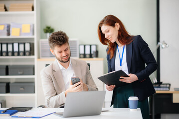 Two business workers talking on the smartphone and using laptop at office.
