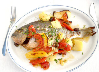 Dorada baked with vegetables on white plate. Isolated photo on white background for design. Food and natural seafood. 