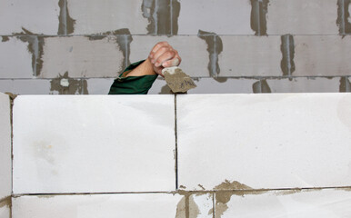 A man is working on a wall, using a trowel to spread cement