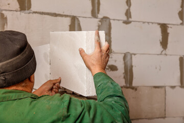 A man is holding a white block of concrete