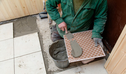 A man is laying tiles on a floor