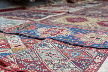 A collection of colorful rugs with various patterns and designs. The rugs are laid out on a...
