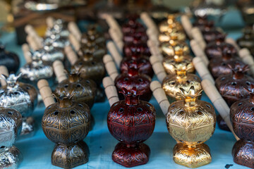 A row of small, ornate vases are displayed on a table. The vases are of different colors and sizes, and they are arranged in a neat row. Scene is one of elegance and sophistication