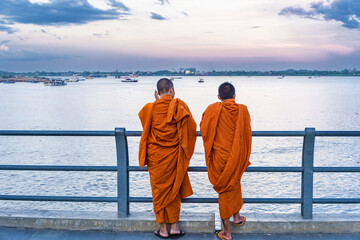two monks watching the sunset over the Mekong River in Phnom Penh Cambodia