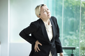 Unwell and sick middle aged woman in office syndrome Distress, Dealing with lower back pain,...