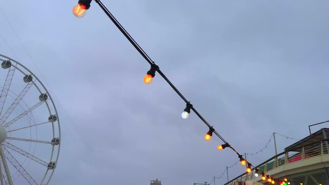 Eine bunte Lichterkette wird durch heftigen Wind hin- und hergeweht, Scheveningen, Niederlande