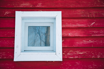 There is a white window that is placed on a bright red wall, creating a striking contrast that...