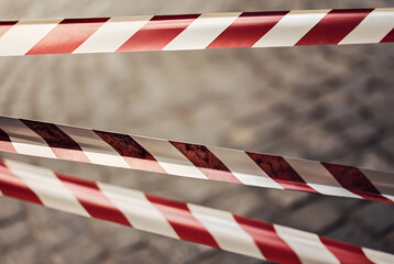 Fototapeta premium Tape barrier marking a danger zone on a stone-paved city sidewalk