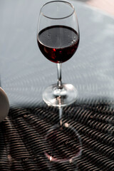 A glass of red alcoholic drink or wine on a glass table on the veranda. The concept of alcoholism, a party, or a holiday.