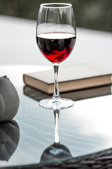 A glass of red alcoholic drink or wine on a glass table on the veranda. The concept of alcoholism, a party, or a holiday.