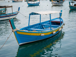 Obraz premium Luzzu - Traditional Maltese Wooden Boat Docked in Quiet Coastal Marina