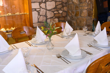 Elegant Table Setting with Fresh Flowers and Napkins in a Cozy Mediterranean Restaurant