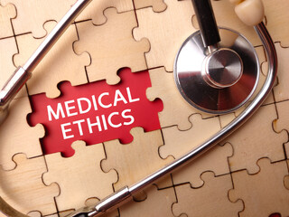 Stethoscope and wooden puzzle with the word MEDICAL ETHICS on a red background