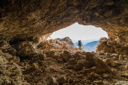 Explorer and Backpacker stands  at the entrance of a large cave