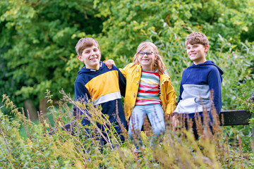 Fototapeta premium Three siblings children. Two kids boys and little girl having fun together on nature