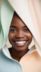 A joyful African American woman smiling brightly, framed by pastel-colored fabric. Beauty, confidence, positivity, and elegance concept