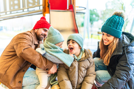 Happy family having fun on a playground slide in winter