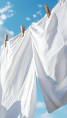 Clean white laundry hanging on a clothesline with blue sky and a few white clouds as background