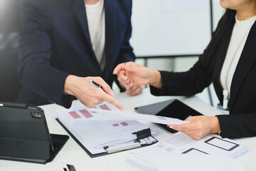 Cropped shot of businesspeople in formal suit discussing documents and data at office desk