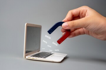 A hand holding a magnet near a laptop screen with the word 