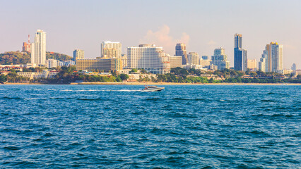 Obraz premium Pattaya city view on the beach with sea or bright blue sky as the foreground and speedboats and beautiful blue sky in Chonburi province, Thailand.