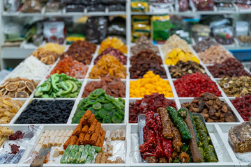 A table full of different colored dried fruits and nuts. The table is covered with a variety of dried fruits and nuts, including dried apricots, dried figs, dried cherries, and dried peaches