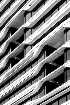 An abstract depiction of a building facade characterized by striking wavy patterns and sharp angles, contrasting with a sleek monochrome aesthetic that draws the eye.