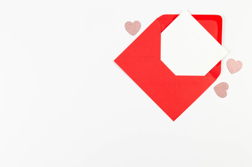 Top view of red envelope, white card on white background. Valentine's day, pink glitter hearts,...
