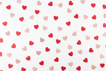 Top view of red and pink glitter hearts on white background. Valentine's day, pink glitter hearts, red hearts, love wallpaper. Flat lay, copy space.