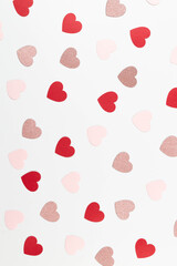 Top view of colorful hearts on white background. Pink glitter hearts, red hearts, pink hearts. Valentine's day, love wallpaper. Flat lay, copy space.