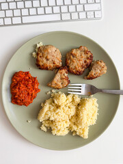 Homemade meal served on a neutral plate, featuring couscous, meat patties and a side of ajvar. Simplicity and balance of the dish reflect a casual yet thoughtful approach to everyday dining. Lunch