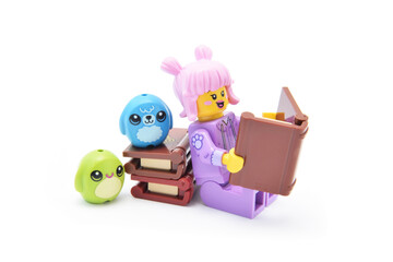 Naklejka premium Lego minifigure of reading girl with a book isolated on white. Editorial illustrative image of hobby and learning. 27th edition.