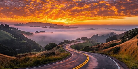 A scenic highway with double yellow lines leading to a breathtaking sunset, surrounded by a rural landscape with rolling hills and a touch of fog.