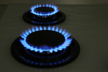 Modern gas cooktop with burning blue flames in kitchen at night