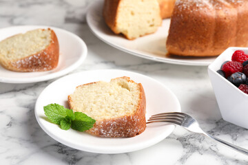 Freshly baked sponge cake, mint and berries on white marble table, closeup