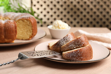 Pieces of freshly baked sponge cake, server and ice cream on wooden table, closeup