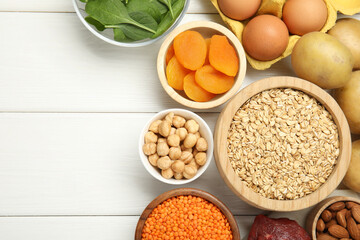 Different products rich in iron on white wooden table, flat lay. Space for text