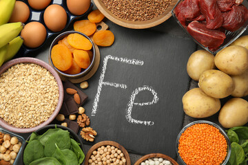 Diet plan for anemia. Different products rich in iron and slate board with Ferrum symbol on table, flat lay. Space for text