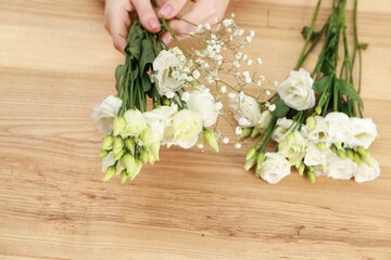 Florist making beautiful wedding bouquet at wooden table, top view