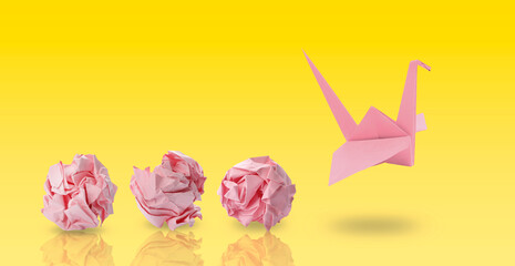 Pink origami crane and crumpled paper balls on yellow gradient background, banner design. Transformation or new ideas concept