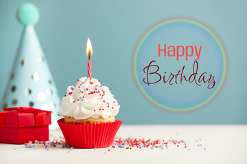 Happy Birthday greeting card. Sweet cupcake with burning candle on light blue background