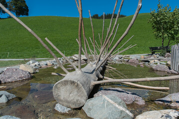 Wooden structure resembling a large skeletal frame placed in a serene natural setting, reflecting...