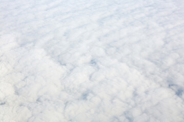 Aerial view over surface of white dense clouds