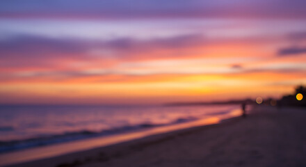 Fototapeta premium Blurred beach scene at sunset, showcasing vibrant colors blending in the sky and reflecting on the water's surface