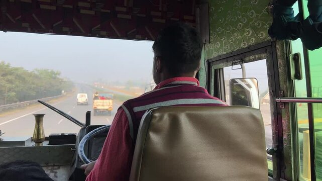 Back view of Bus driver driving by handling steering wheel. Highway driving.