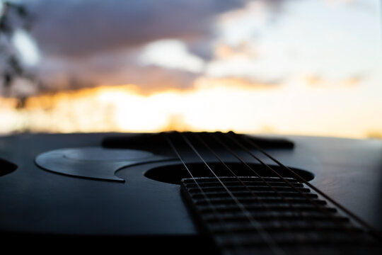 A Beautiful CloseUp of an Acoustic Guitar Silhouette Set Against a Stunning Sunset Background - Powered by Adobe